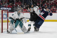 San Jose Sharks defenseman Jaycob Megna, center, knocks over Washington Capitals center Nic Dowd as Sharks goaltender James Reimer (47) defends the goal during the first period of an NHL hockey game, Wednesday, Jan. 26, 2022, in Washington. (AP Photo/Evan Vucci)