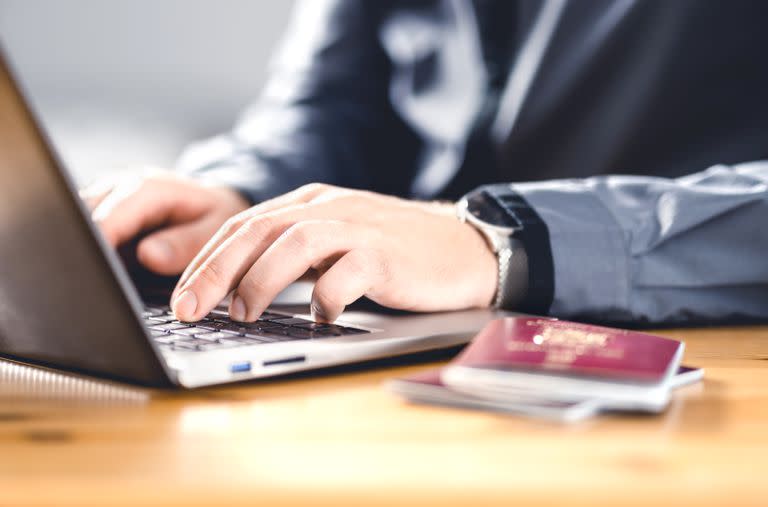 Man with passport and laptop. Travel document and identification. Immigrant writing electronic application for citizenship. Apply for digital visa. Online flight ticket or web check in. Ciberdelito