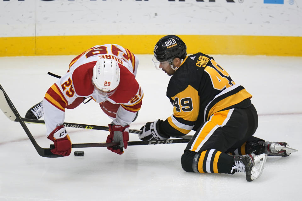 Pittsburgh Penguins' Dominik Simon (49) and Calgary Flames' Dillon Dube (29) fall to the ice after colliding during the first period of an NHL hockey game in Pittsburgh, Thursday, Oct. 28, 2021. (AP Photo/Gene J. Puskar)