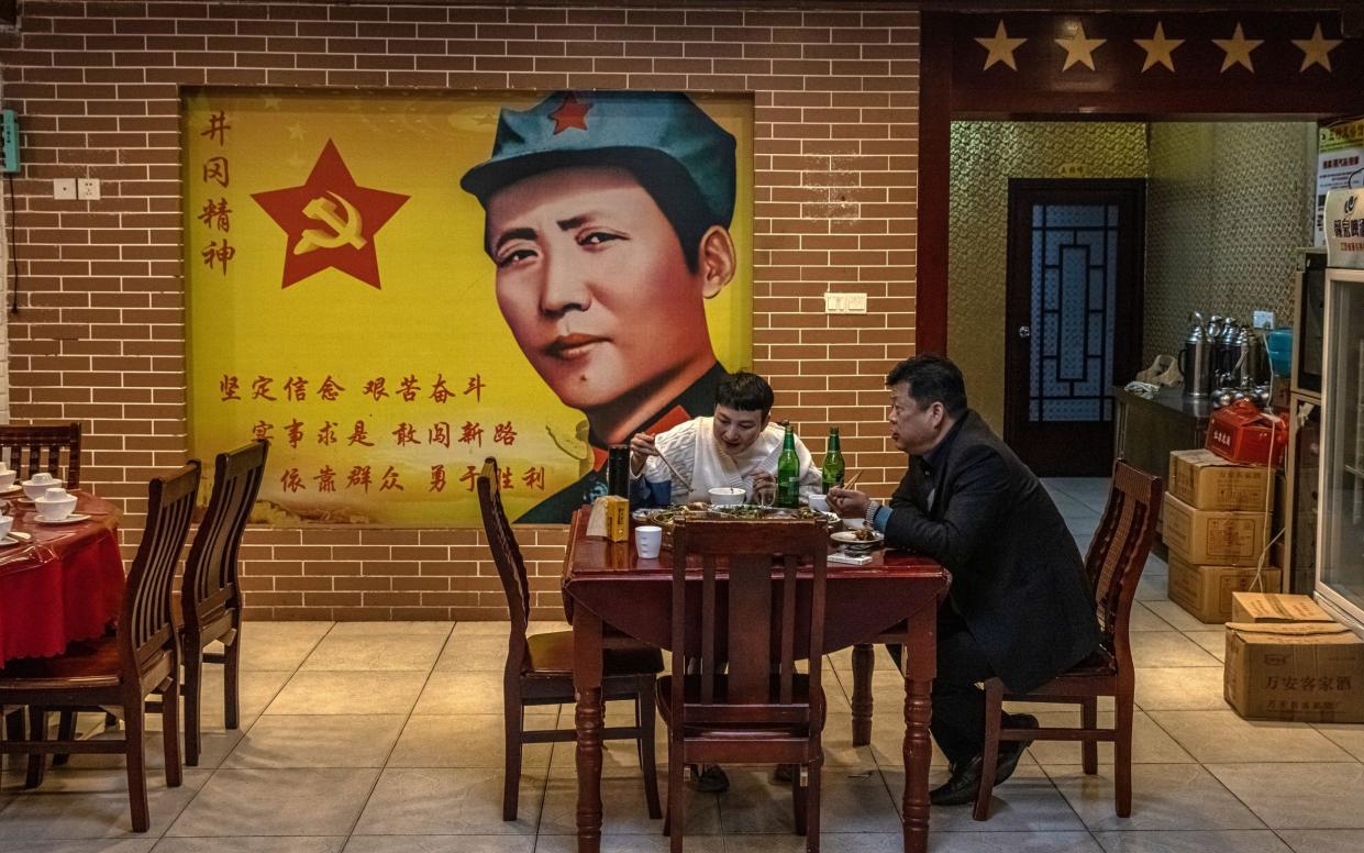 People eat under the watchful gaze of former Chinese leader Mao Zedong in a restaurant in Jinggangshan, a historically important area where the Communist Party found its first rural base in 1927 - ROMAN PILIPEY/EPA-EFE/Shutterstock 