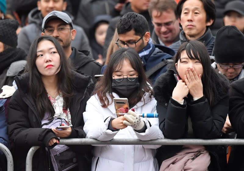 A spectator wears a mask as she watches the Changing of the Guard ceremony outside of Buckingham Palace in London