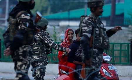 Indian security personnel stop Kashmiri residents as they stand guard on a deserted road during restrictions after scrapping of the special constitutional status for Kashmir by the Indian government, in Srinagar