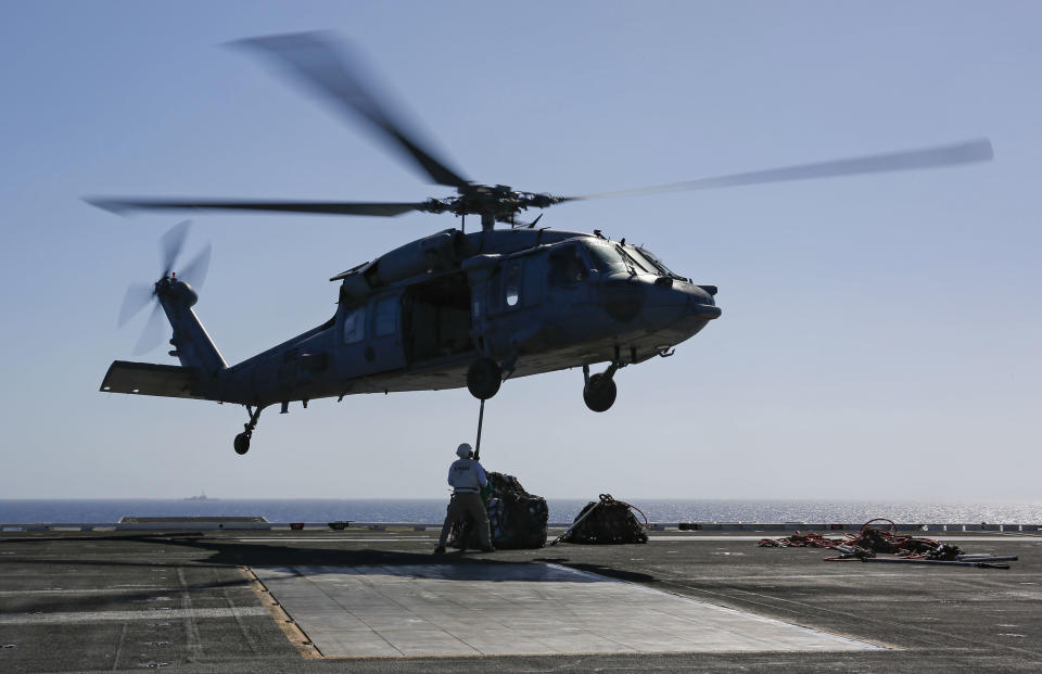 In this Friday, May 10, 2019 photo released by the U.S. Navy, logistics specialists attach cargo to an MH-60S Sea Hawk helicopter on the flight deck of the Nimitz-class aircraft carrier USS Abraham Lincoln in the Persian Gulf. The aircraft carrier strike group is being deployed to the Persian Gulf to counter an alleged but still-unspecified threat from Iran. (Mass Communication Specialist 3rd Class Amber Smalley, U.S. Navy via AP)