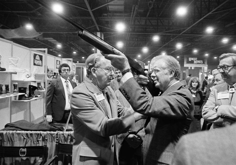 Former President Jimmy Carter holds a shotgun at the NSSF's trade show in Atlanta in 1984. (Ric Feld / AP file)