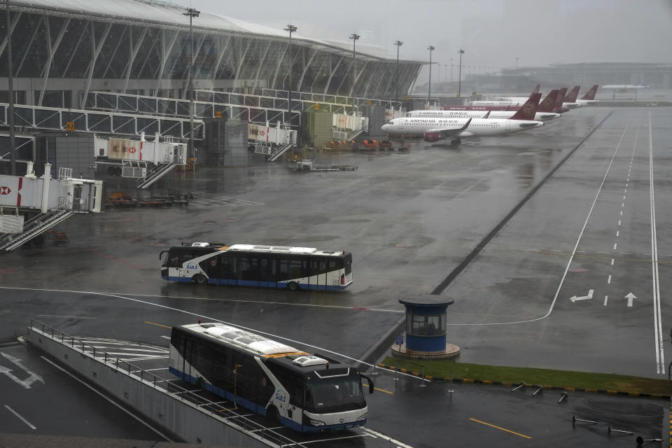 Buses and passenger airplanes are parked on the tarmac after all flights were canceled at Pudong International Airport in Shanghai, China, Sunday, July 25, 2021. Airline flights were canceled in eastern China and cargo ships were ordered out of the area Saturday as Typhoon In-fa churned toward the mainland after dumping rain on Taiwan. (AP Photo/Andy Wong)