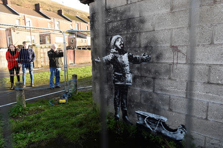 People view new work by the artist Banksy that appeared during the week on the walls of a garage in Port Talbot, Britain December 22, 2018. REUTERS/Rebecca Naden