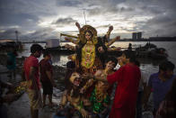 Devotos hindúes se aprestan a arrojar al agua a la diosa Durga en el río Hooghly, tributario del Ganges, en Kolkata, al este de la India, el 9 de octubre del 2019. Cientos de miles de ídolos religiosos son arrojados al Ganges y otros ríos durante el festival de Durga Puja todos los años. (AP Photo/Altaf Qadri)