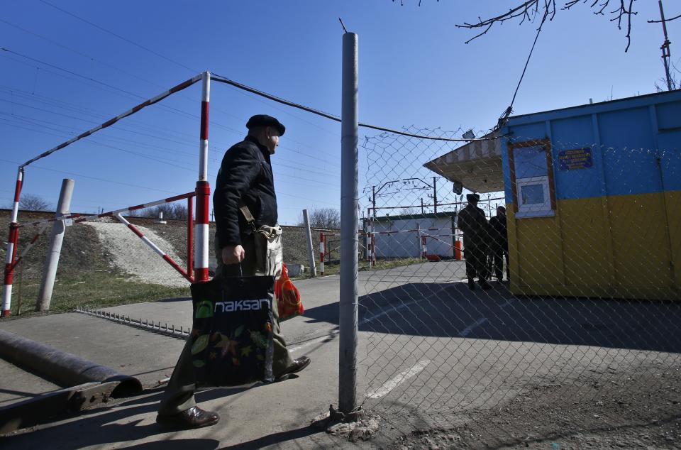 In this photo taken Monday, March 24, 2014, a man crosses the Ukrainian-Russian border in the village of Vyselki, eastern Ukraine. Ever since the 1991 breakup of the Soviet Union, the village of Vyselki has been split between Ukraine and Russia. For years its residents have continued to live together peacefully, doing most of their shopping in one country and paying their electricity bills in another. But after Russia seized the Crimean Peninsula from Ukraine, the Ukrainian villagers fear a further incursion of Russian troops, while the Russians say they would welcome their protection against the new pro-Western government in Kiev. (AP Photo/Sergei Grits)