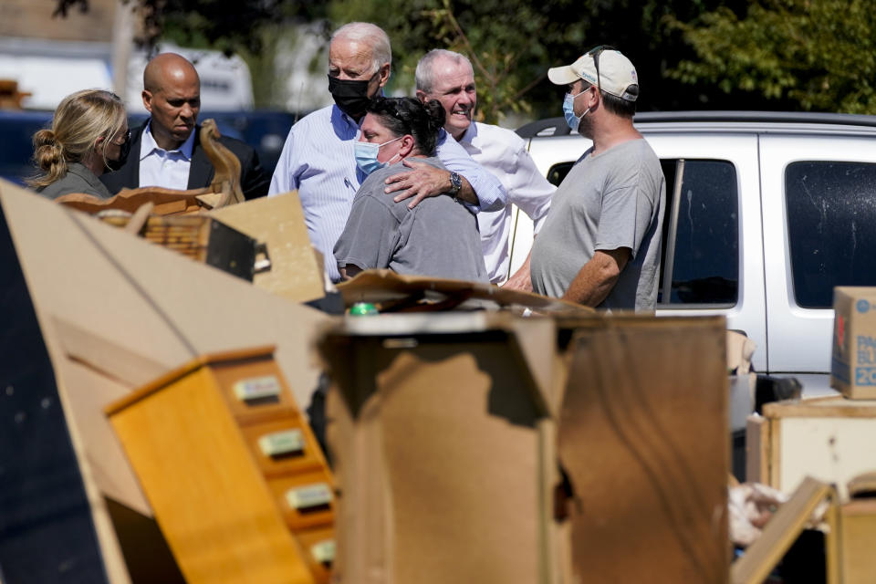 FILE - President Joe Biden hugs a person as he tours a neighborhood impacted by Hurricane Ida, Tuesday, Sept. 7, 2021, in Manville, N.J. Sen. Cory Booker, D-N.J., second from left, and New Jersey Gov. Phil Murphy, second from right, look on. (AP Photo/Evan Vucci, File)