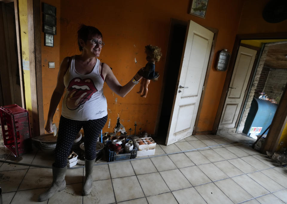 Resident Carine Lacroix holds up a doll she rescued from her flood damaged home in the La Brouck neighborhood of Trooz, Belgium, Tuesday, July 27, 2021. Lacroix and her companion still find it hard to sleep after they feared for their lives during deadly floods nearly two weeks ago, isolated and trapped in the top floor of their house for two days before they were rescued on a small boat by firefighters. (AP Photo/Virginia Mayo)