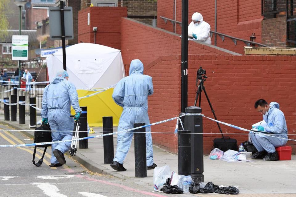 Investigation: Forensic officers at the scene of the stabbing in Finsbury Park (EPA)