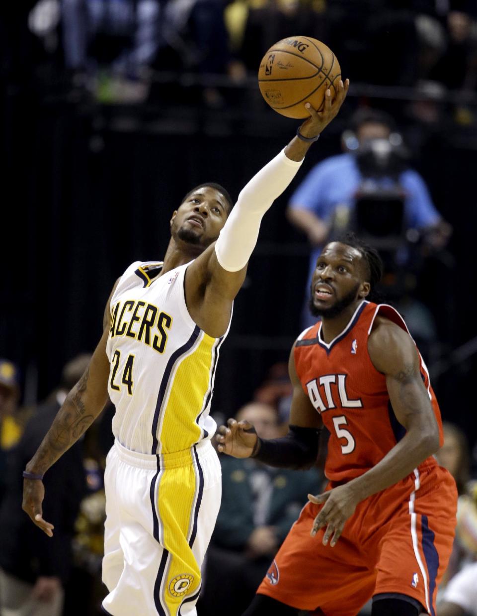 Indiana Pacers' Paul George (24) reaches for the ball as Atlanta Hawks' DeMarre Carroll (5) defends during the first half in Game 5 of an opening-round NBA basketball playoff series Monday, April 28, 2014, in Indianapolis. (AP Photo/Darron Cummings)