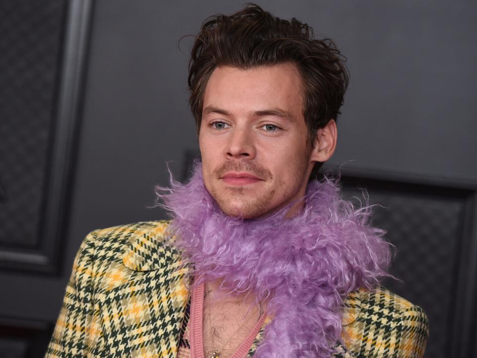 Harry Styles wears a plaid jacket and purple feather boa at the 2021 Grammys.