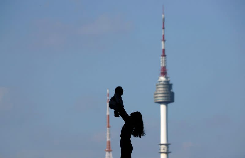 FILE PHOTO: A woman holding up her baby is silhouetted against the backdrop of N Seoul Tower in Seoul