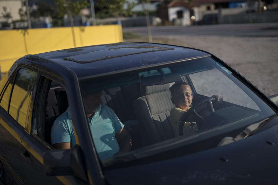 Redi Sakaj, un niño de seis años, conduce un coche en el depósito de chatarra en el que trabaja su padre. (Foto: Daniel Cole / AP).