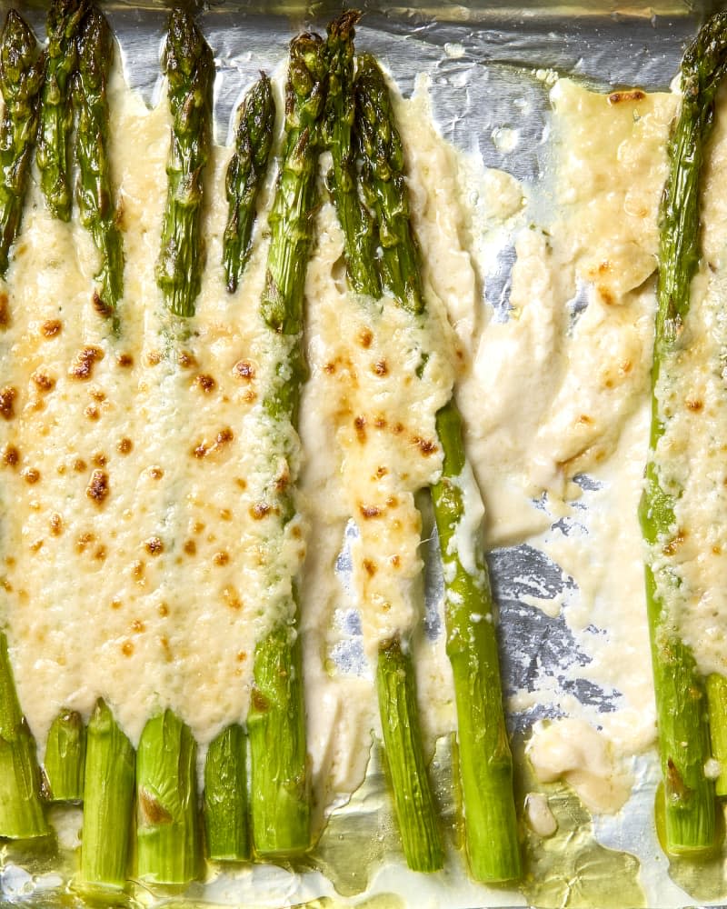overhead shot of baked alfredo asparagus on a baking sheet.