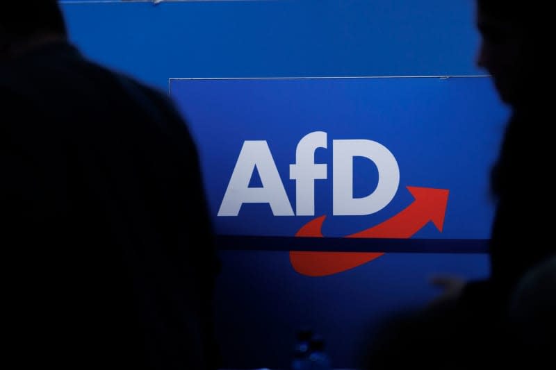 Delegates walk in front of the party logo at the AfD federal party conference in Magdeburg. Carsten Koall/dpa