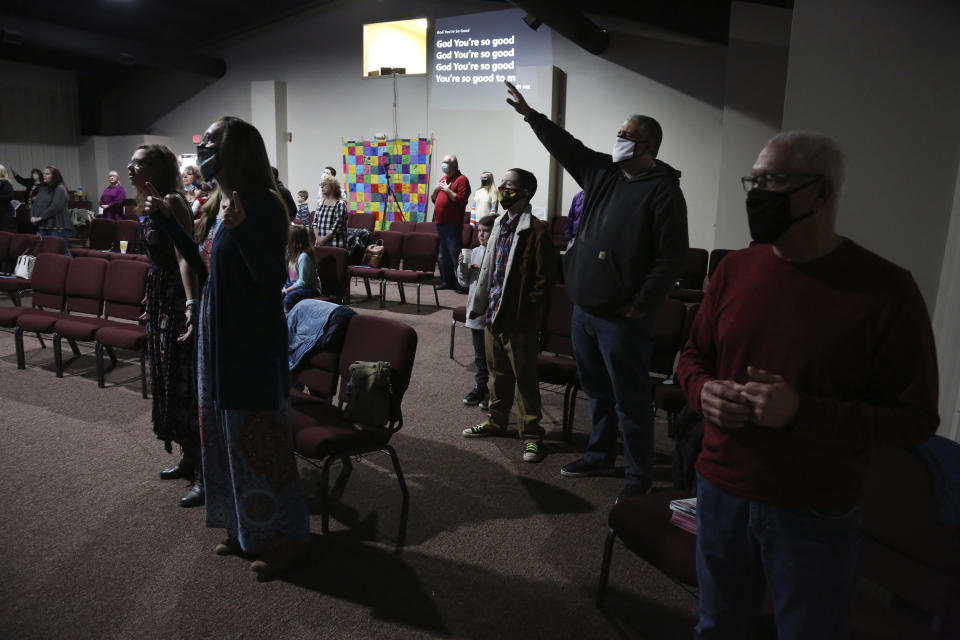 Travis Lowe, second from right, pastor of Crossroads Church in Bluefield, W.Va., raises his arm during services Sunday Jan. 23, 2021. Lowe, who has expressed concern over the divisiveness of American politics, believes collaboration by churches will help heal his town and the country. (AP Photo/Jessie Wardarski)