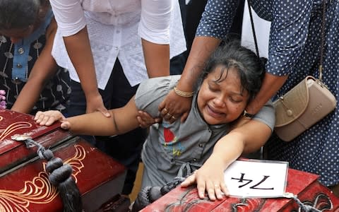 Grief stricken relatives collapsed into the arms of bystanders during the mass funeral - Credit: &nbsp;ATHIT PERAWONGMETHA/REUTERS