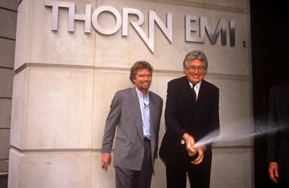 Richard Branson pictured on March 6, 1992, in London standing under a sign that read "Thorn EMI" next to Thorn EMI Chairman Sir Colin Southgate, who is spraying champagne after announcing the sale of Virgin Music to Thorn EMI for $ 1 billion.