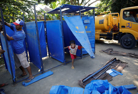 A boy plays in portable showers being assembled at a temporary evacuation center for people living near Mount Agung, a volcano on the highest alert level, in Manggis, on the resort island of Bali, Indonesia, September 28, 2017. REUTERS/Darren Whiteside