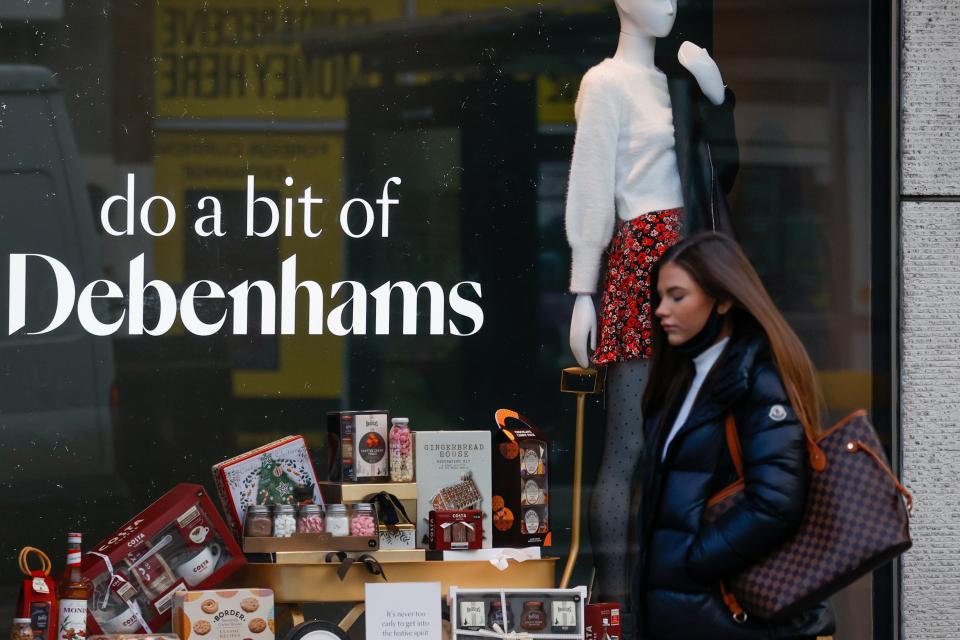 <p>Closures: A woman walks past a Debenhams store</p> (REUTERS)