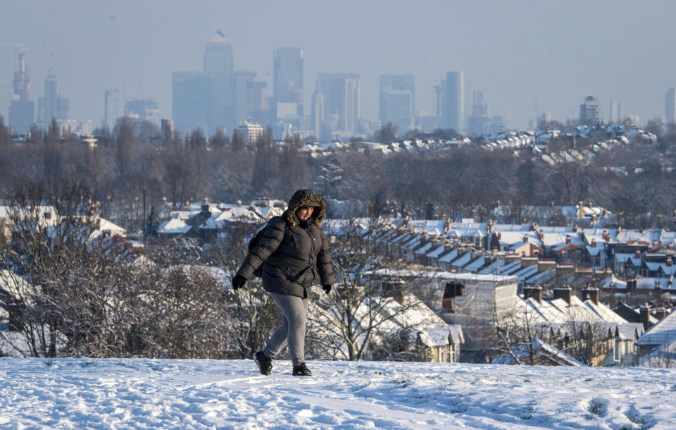 <p>A woman walks over Blythe Hill in south London. Britain, which is buffered by the Atlantic Ocean and tends to have temperate winters, saw heavy snow in some areas that disrupted road, rail and air travel and forced hundreds of schools to close. (Dominic Lipinski/PA via AP) </p>