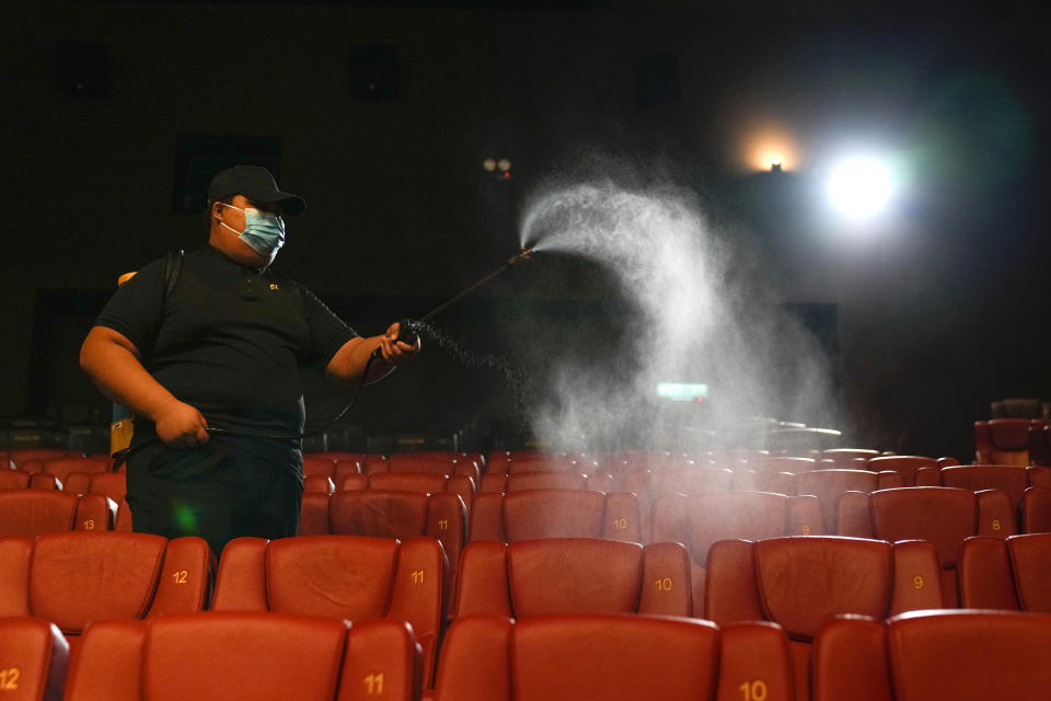 Movie cinema staff spray disinfectant in preparation for its reopening at a shopping mall in Kuala Lumpur, Malaysia, Wednesday, Sept. 8, 2021. Malaysia's government announced the reopening of most entertainment and art sectors to fully vaccinated individuals in all states beginning Sept 9. (AP Photo/Vincent Thian)