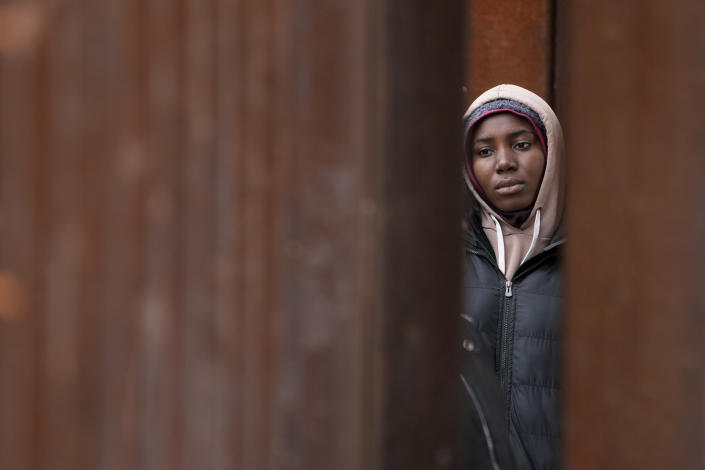 A migrant woman waits between two border walls hoping to apply for asylum, a day after the Title 42 cutoff, as seen from San Diego, May 12, 2023. Mexico is flying migrants south away from the U.S. border to keep migrants from massing in its border cities. (AP Photo/Gregory Bull)