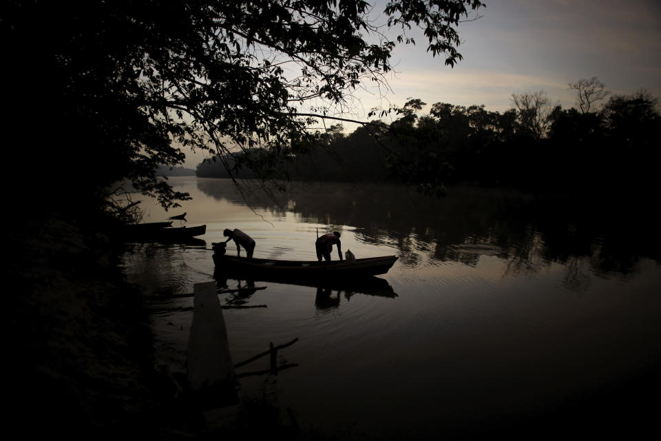 Tenetehara Indigenous men prepare to go out on their boat in the Gurupi River, in the Alto Rio Guama Indigenous Territory, where they have enforced six months of isolation during the COVID-19 pandemic, near the city of Paragominas, state of Para, northern region of Brazil, Monday, Sept. 7, 2020. The Indigenous group, also known as Tembe, held a festival this week to celebrate and give thanks that none of their members have fallen ill with COVID-19, after closing their area off in March. (AP Photo/Eraldo Peres)