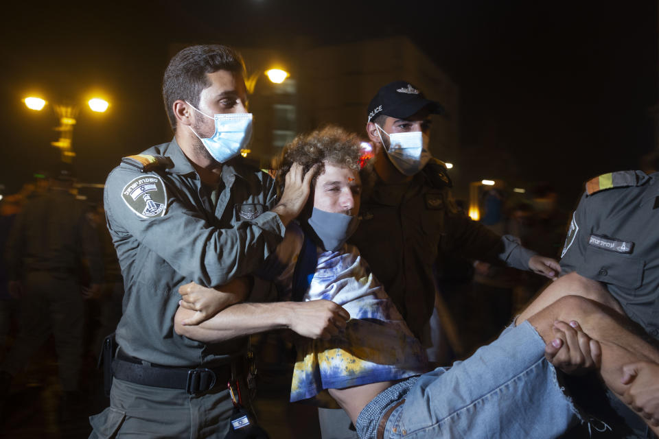 Police carry away a protester as they clear the square outside of Israeli Prime Minister Benjamin Netanyahu's residence in Jerusalem, early Sunday, Aug. 30, 2020. Thousands of Israelis demonstrated in Jerusalem in a continuation of summer-long weekend rallies demanding the resignation of Netanyahu, who faces a corruption trial and accusations of mishandling the coronavirus crisis. (AP Photo/Maya Alleruzzo)