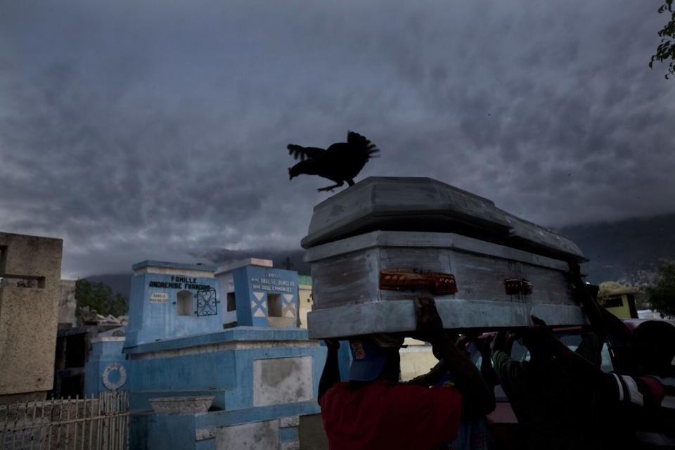 Men carry a coffin to a grave in an overflowing cemetery in Port-au-Prince