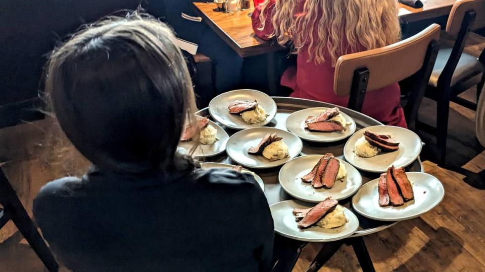 A staff member brings out sample plates of steak and mashed potatoes at the ribbon-cutting event for Outback Steakhouse in O’Fallon.