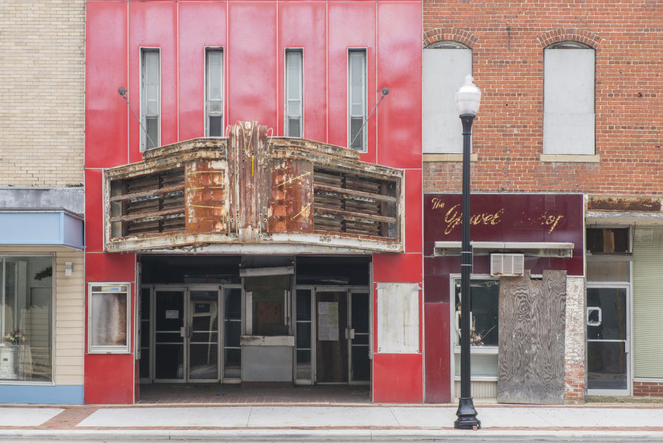 זהו תצלום צבעוני אופקי של בית קולנוע סגור בעיירה קטנה באמריקה.