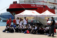 FILE PHOTO: Migrants sit on the ground after disembarking from Vos Hestia ship of NGO "Save the Children" in the Sicilian harbour of Augusta, Italy August 4, 2017. REUTERS/Antonio Parrinello/File Photo