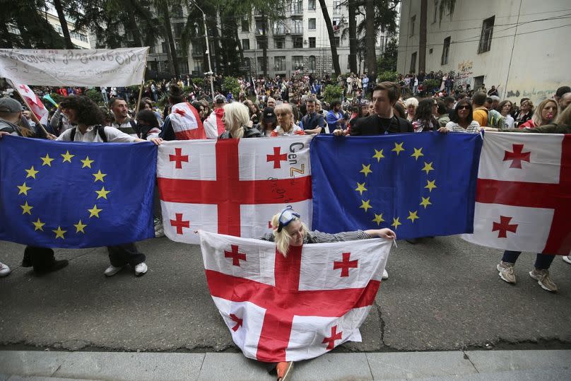 Demonstrators with Georgian national and EU flags gather in front of police during an opposition protest against the foreign influence bill in Tbilisi, Georgia.