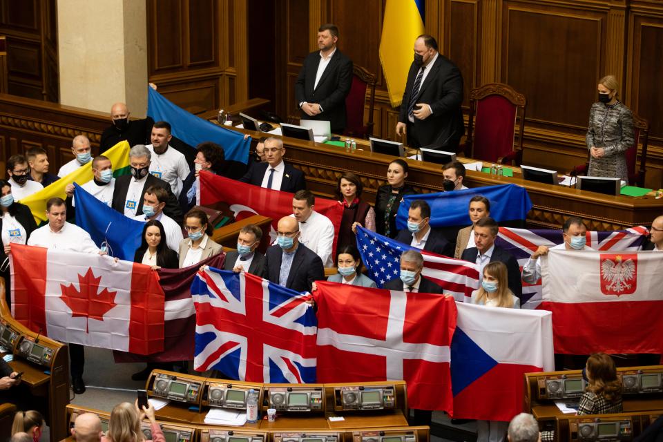 Ukrainian lawmakers hold state flags of Ukraine's partners to show their appreciation of political support and military aid during a session of parliament in Kyiv, Ukraine, on  Feb. 1, 2022.