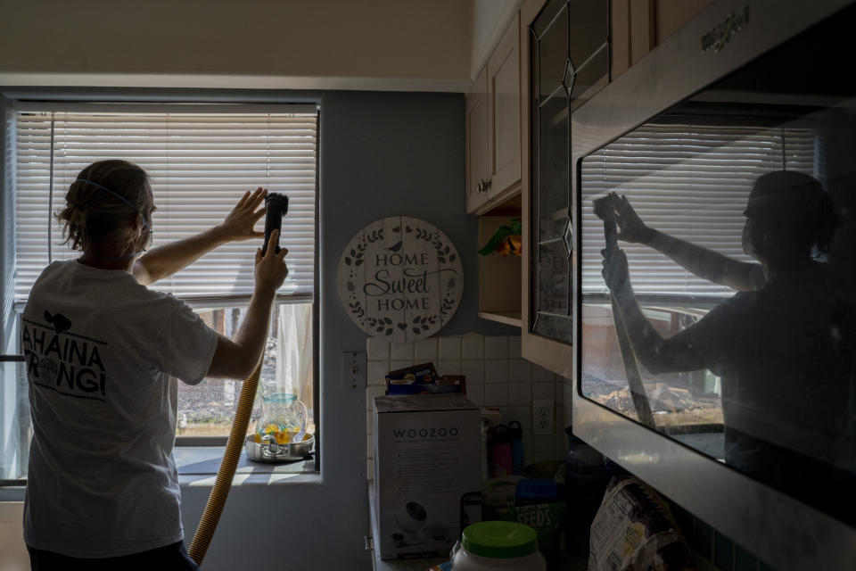 Daniel Skousen vacuums his home, damaged by August's wildfire, on Friday, Nov. 3, 2023, in Lahaina, Hawaii. Skousen stated he will not deep clean his home until the EPA removes all debris from the burnt house adjacent to his. (AP Photo/Mengshin Lin)