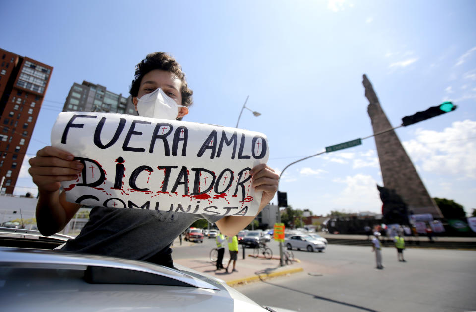 A demonstrator displays a sign reading "AMLO Out. Communist Dictator"  during a caravan to protest against the government of Mexican President Andres Manuel Lopez Obrador (ALMO) and his handling of the COVID-19 novel coronavirus pandemic, in Guadalajara, Jalisco State, Mexico, on May 30, 2020. (Photo by Ulises Ruiz / AFP) (Photo by ULISES RUIZ/AFP via Getty Images)