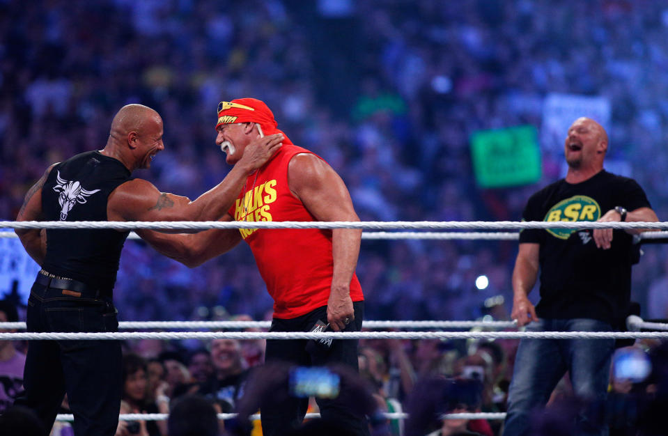 Dwayne Johnson aka The Rock, left, embraces Hulk Hogan, center, as "Stone Cold" Steve Austin looks on during Wrestlemania XXX at the Mercedes-Benz Super Dome in New Orleans on Sunday, April 6, 2014. (Jonathan Bachman/AP Images for WWE)