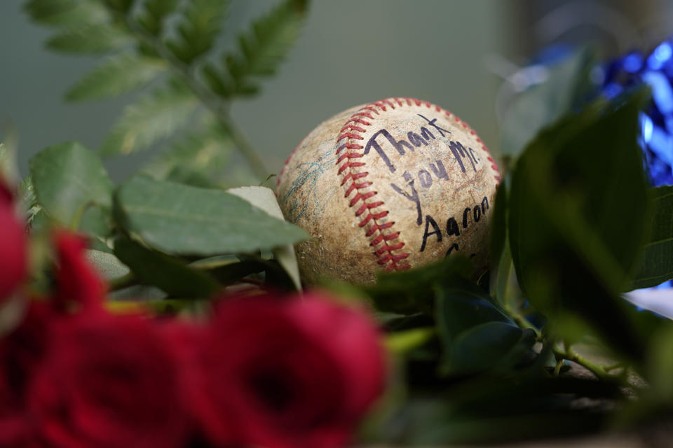 A baseball left by a fan rests in a growing memorial Friday, Jan. 22, 2021, in Atlanta, near the spot where a ball hit for home run by Atlanta Braves' Hank Aaron cleared the wall to break Babe Ruth's home run record in 1974. Aaron, who endured racist threats with stoic dignity during his pursuit of Babe Ruth but went on to break the career home run record in the pre-steroids era, died peacefully in his sleep early Friday. He was 86. (AP Photo/John Bazemore)