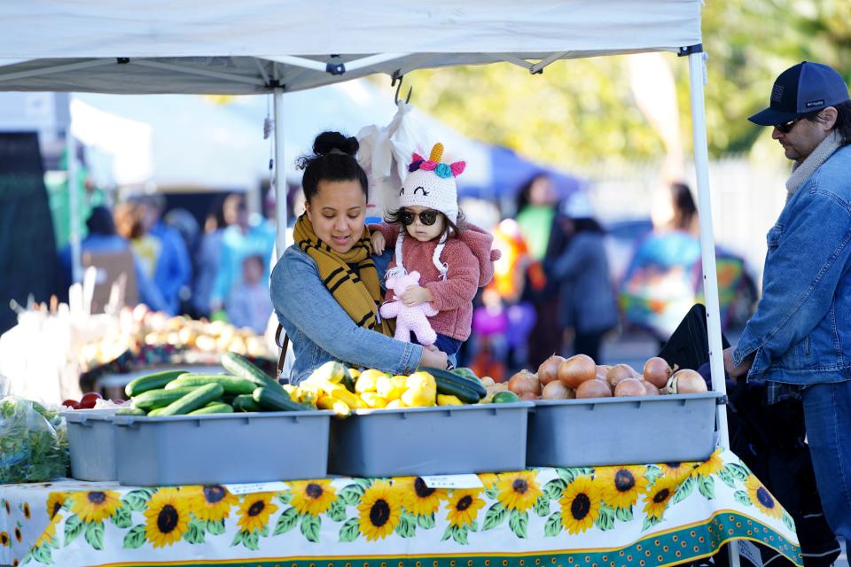 Shoppers come to the seasonal Redding Farmers Market, located behind Redding City Hall. This woman and child checked out squash and onions on Oct. 28, 2023.