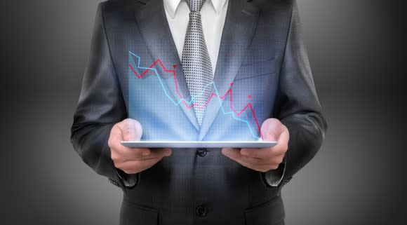 Businessman holding a tablet projecting a falling graph.