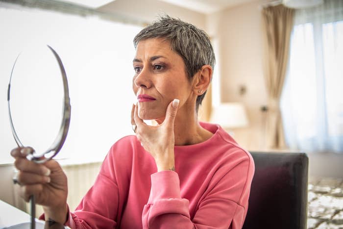 A woman examining her face in the mirror