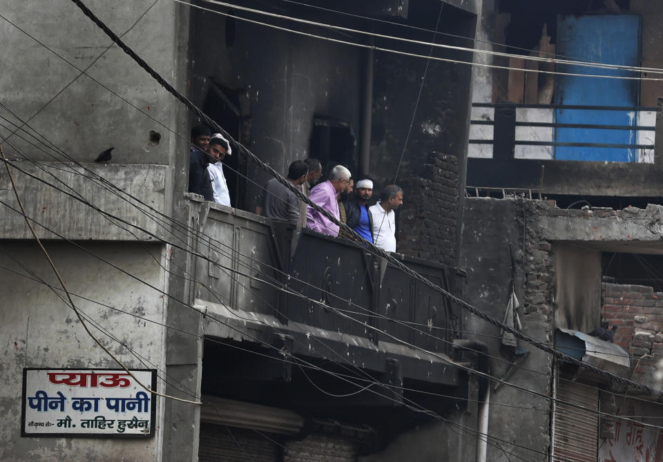 Residents of a burnt building assess the damage following Tuesday's violence in New Delhi, India, Thursday, Feb. 27, 2020. India accused a U.S. government commission of politicizing communal violence in New Delhi that killed at least 30 people and injured more than 200 as President Donald Trump was visiting the country. The violent clashes between Hindu and Muslim mobs were the capital's worst communal riots in decades and saw shops, Muslim shrines and public vehicles go up in flames. Signage in Hindi reads, "Drinking Water".(AP Photo/Rajesh Kumar Singh)