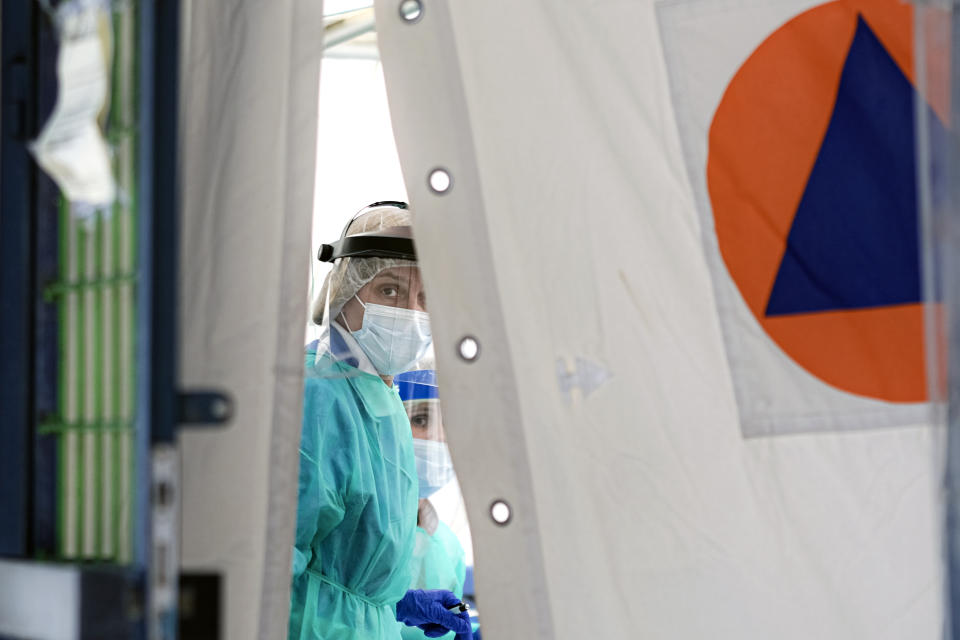 A doctor peers from behind curtains in the triage unit of the University Hospital in Sarajevo, Bosnia, Tuesday, April 7, 2020. Less than three weeks ago, the respected Bosnian epidemiologist Sefik Pasagic was fielding calls from journalists seeking his opinion and advice on how best to prepare for the coronavirus outbreak. The 60-year-old father of four died of complications from the COVID-19 infection which his wife describes as an unnecessarily long and desperate struggle to get the help he needed. (AP Photo/Kemal Softic)