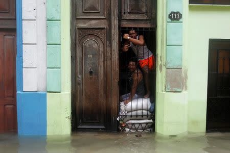 People pose for a photograph as sandbags are placed in the entrance of a home, after the passing of Hurricane Irma, in Havana, Cuba September 10, 2017. REUTERS/Stringer