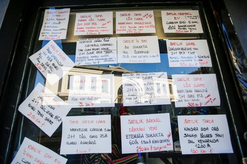 Fliers of houses for rent and sale are stuck on the window of the office of an estate agent in Istanbul