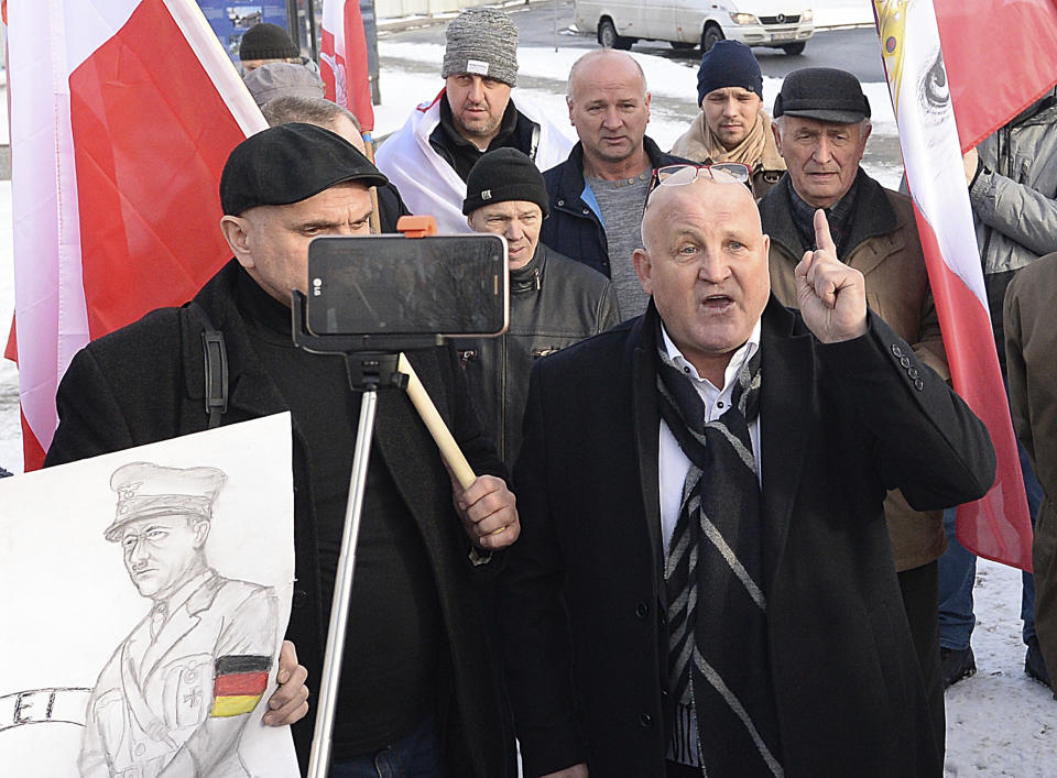 A Polish far-right activist, Piotr Rybak,right, and other nationalists gather outside the memorial site of Auschwitz in Oswiecim, Poland, on Sunday Jan. 27, 2019. Rybak has been imprisoned for burning the effigy of a Jew. He said his gatherings Sunday was an act of protest against the Polish government, which he accuses of remembering only Jews and not murdered Poles in yearly observances at the memorial site.(AP Photo/Czarek Sokolowski)