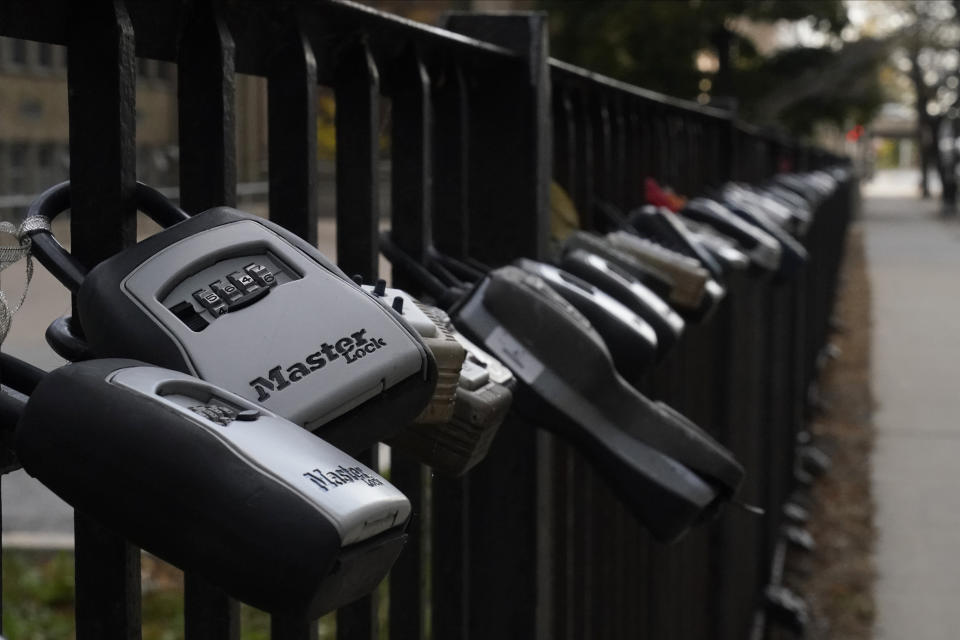 FILE - Key lock boxes for real estate showings hang on a fence outside a high-rise condominium building, Oct. 27, 2022, in Chicago. The cost of hiring a real estate agent to buy or sell a home is poised to change along with decades-old rules that have helped determine broker commissions. (AP Photo/Kiichiro Sato, File)